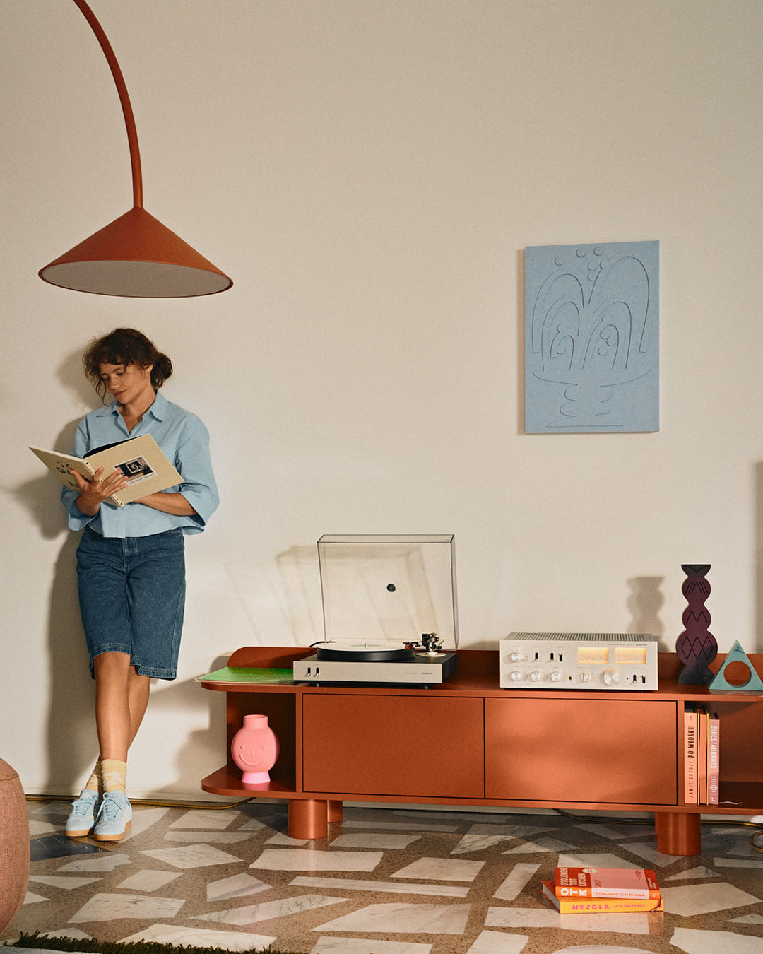 Unitra Audio turntable and amplifier on a cabinet with a woman reading a book