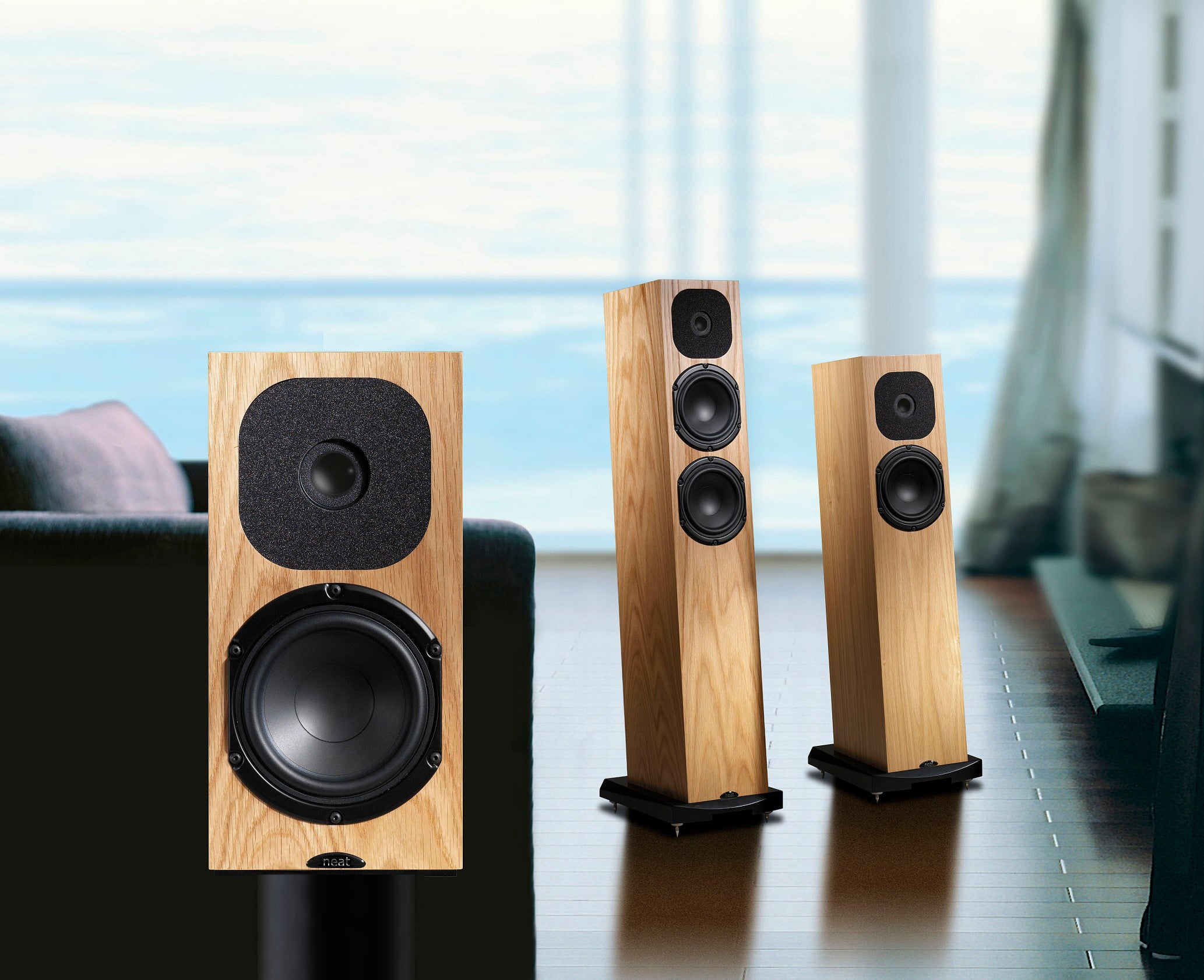 Three wooden Neat speakers on a table with a blurred background